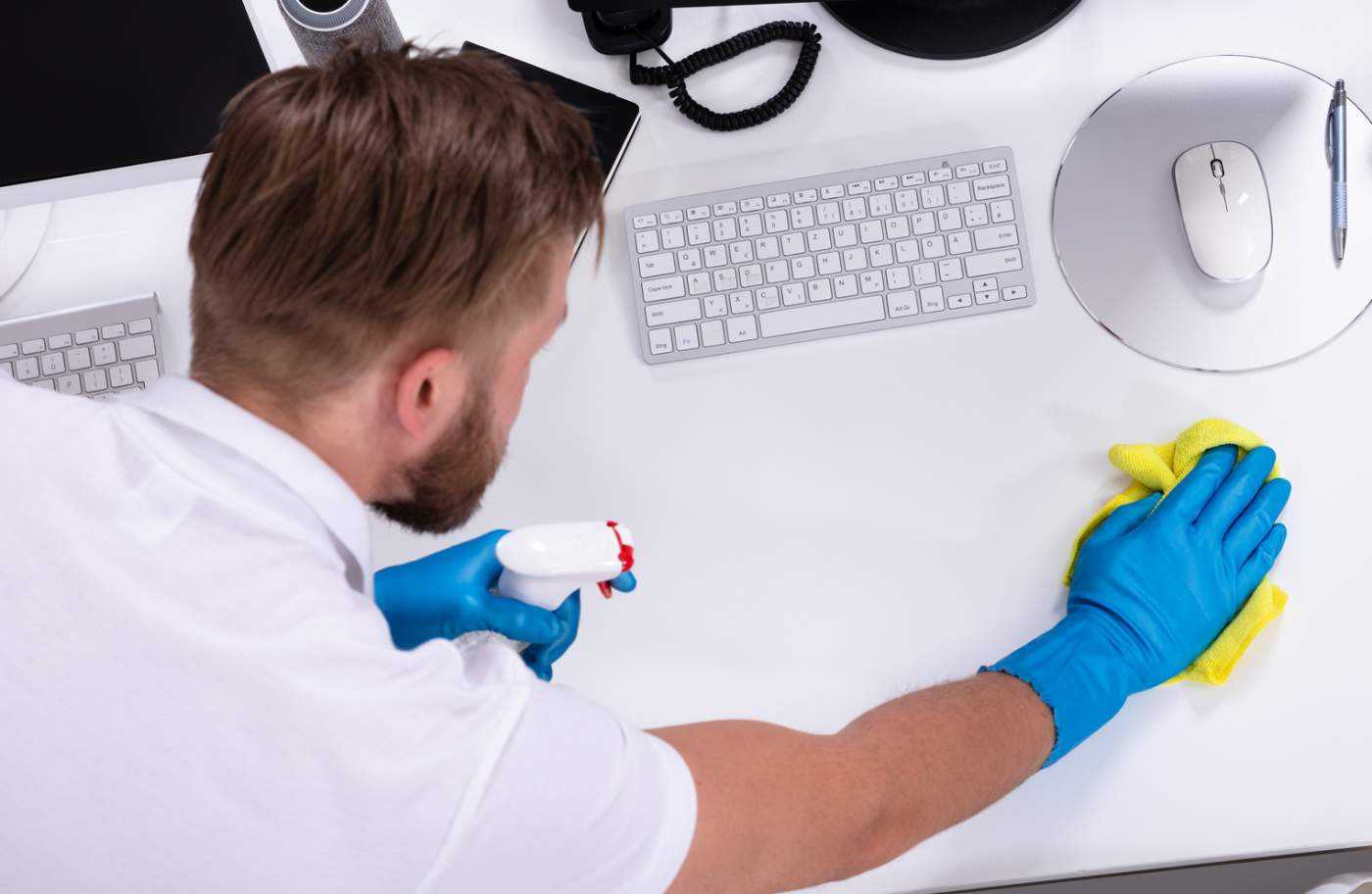 Person Cleaning An Office Desk