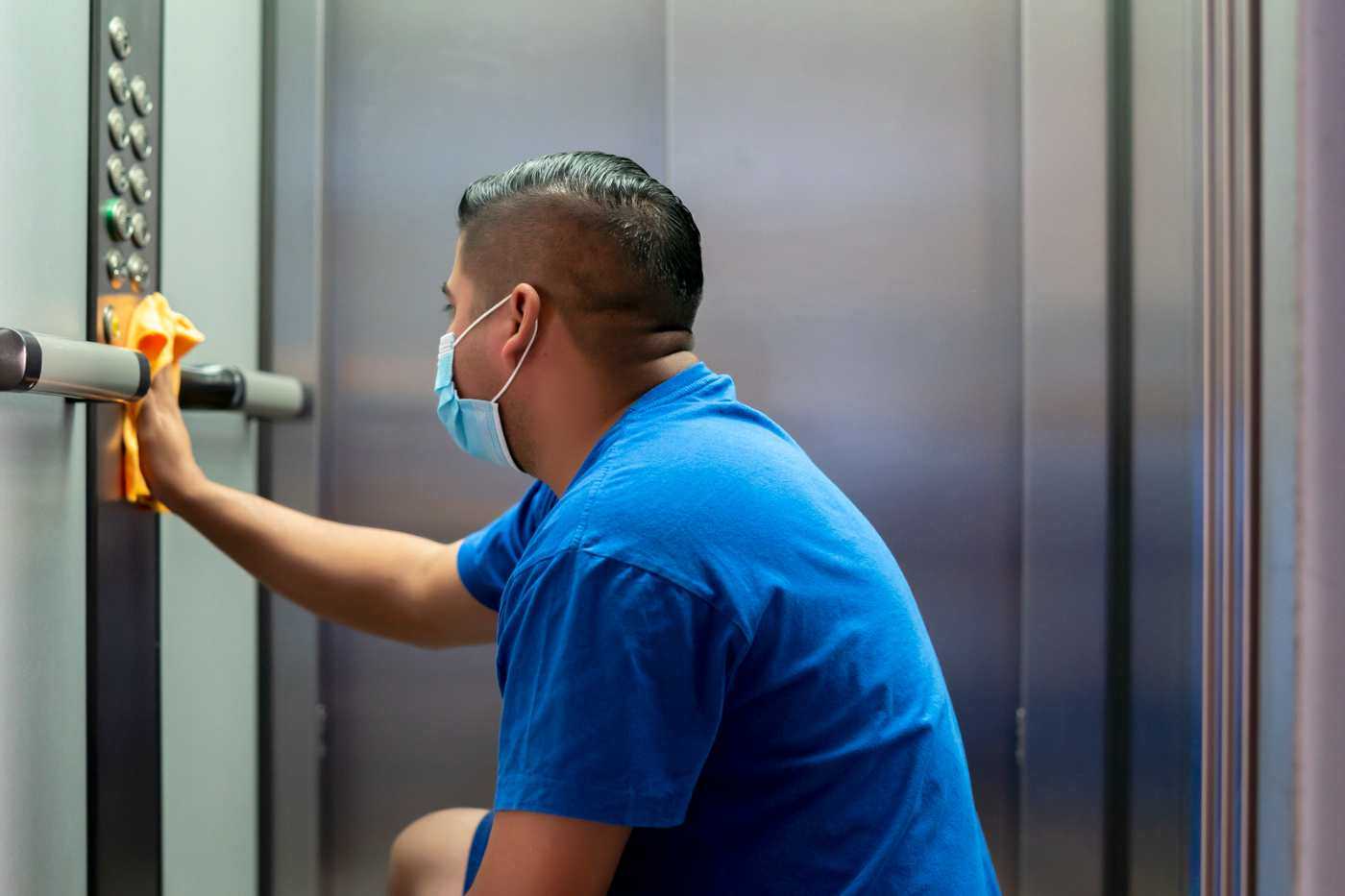 Janitorial Staff Disinfecting Elevator Buttons