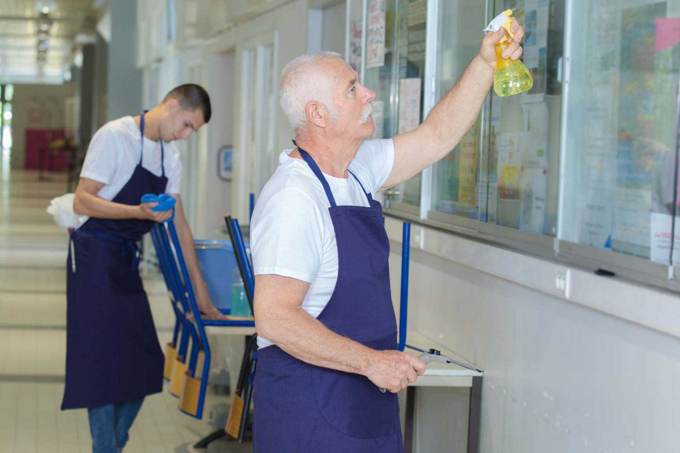Two People From A Janitorial Service Cleaning A School