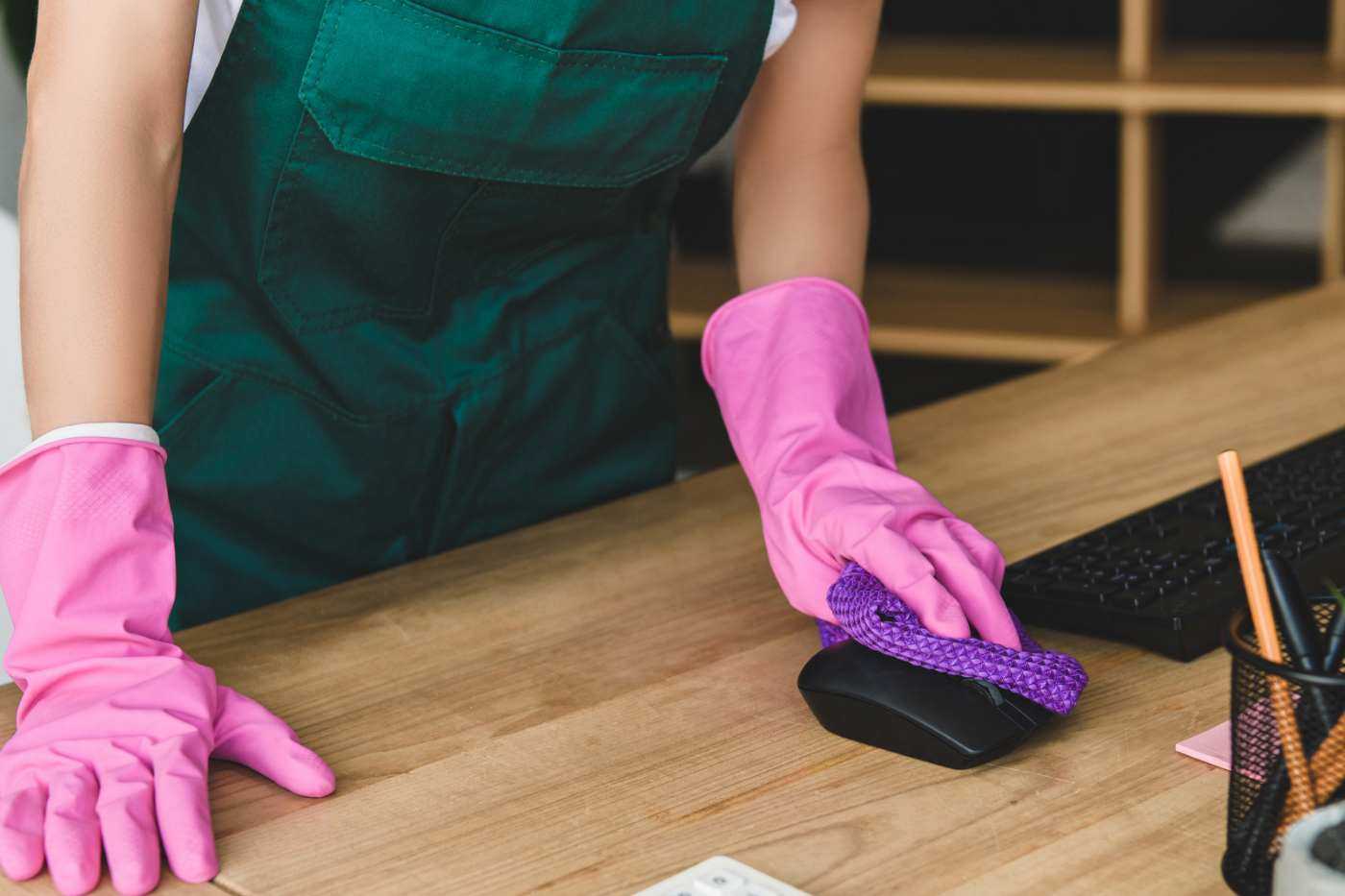 Woman Wearing Rubber Gloves Cleaning Office Desk