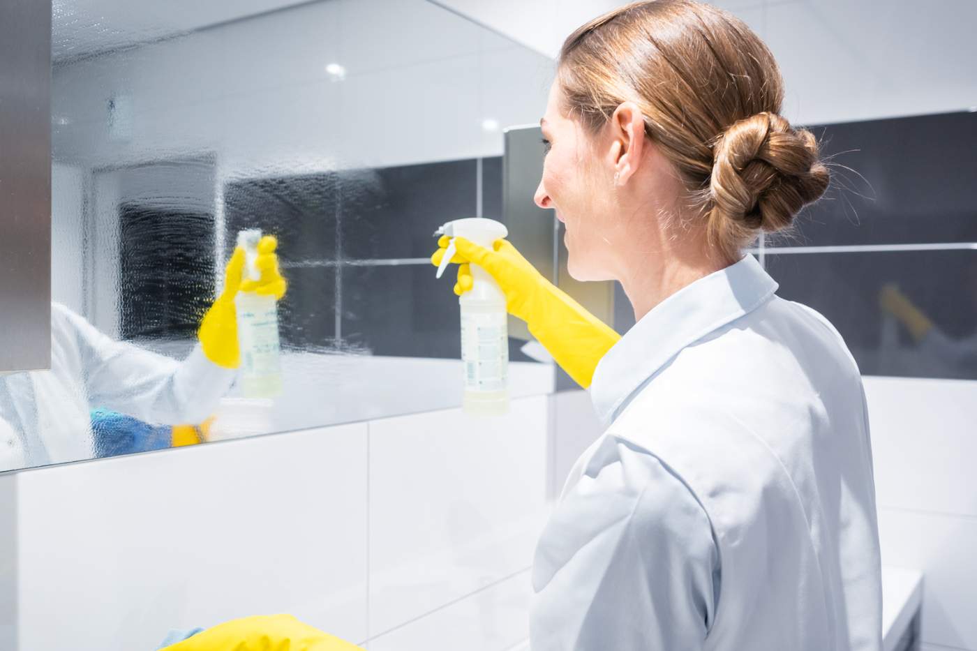 Woman Cleaning Bathroom Mirror